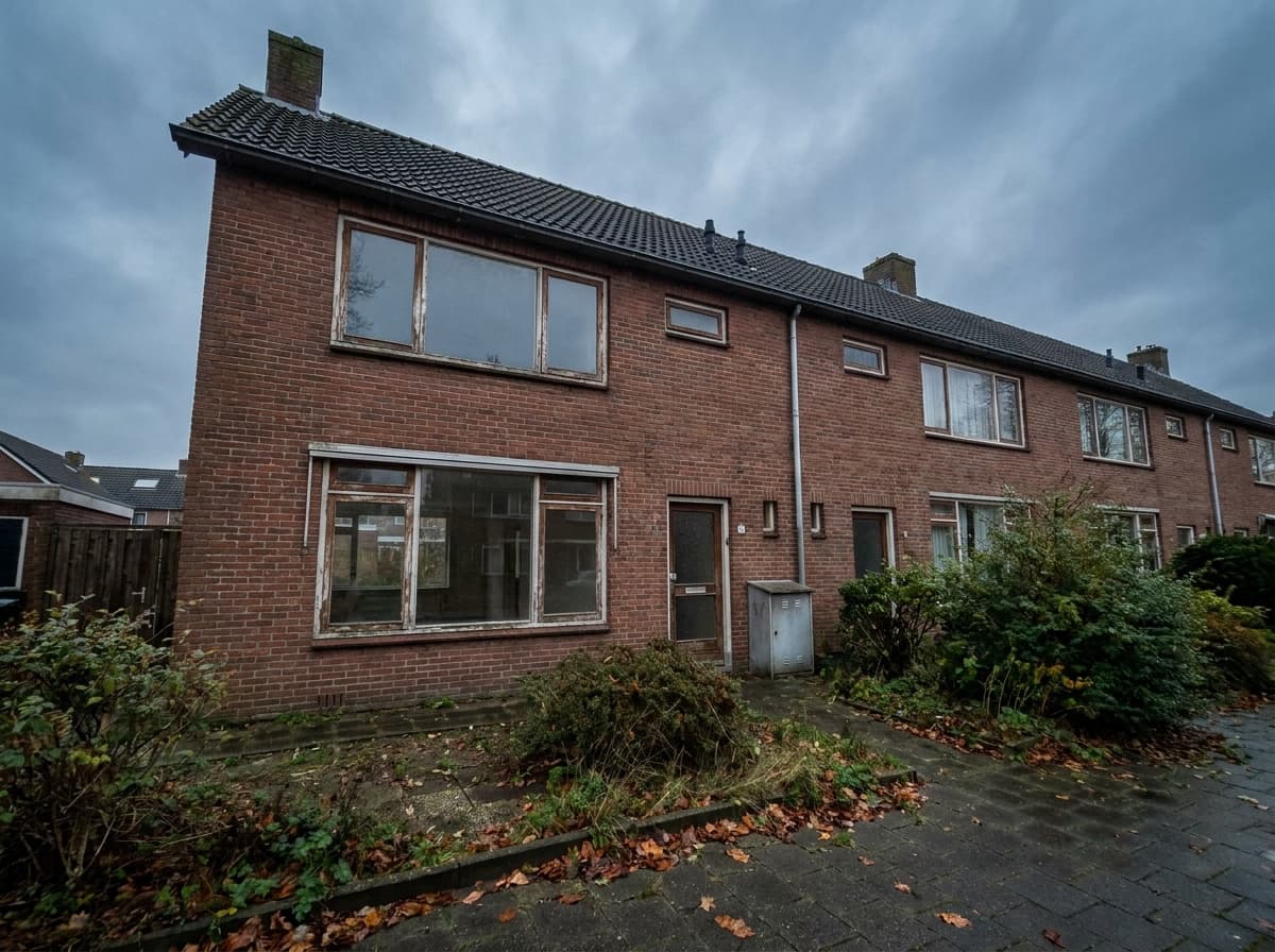 Hele rijwoning verweerd onder een bewolkte Nederlandse lucht