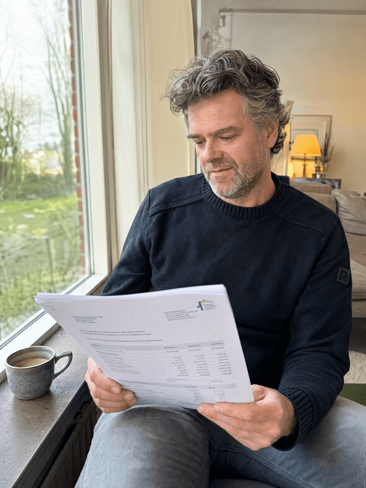 Een ontspannen huiseigenaar leest thuis bij het raam rustig een vrijblijvende offerte